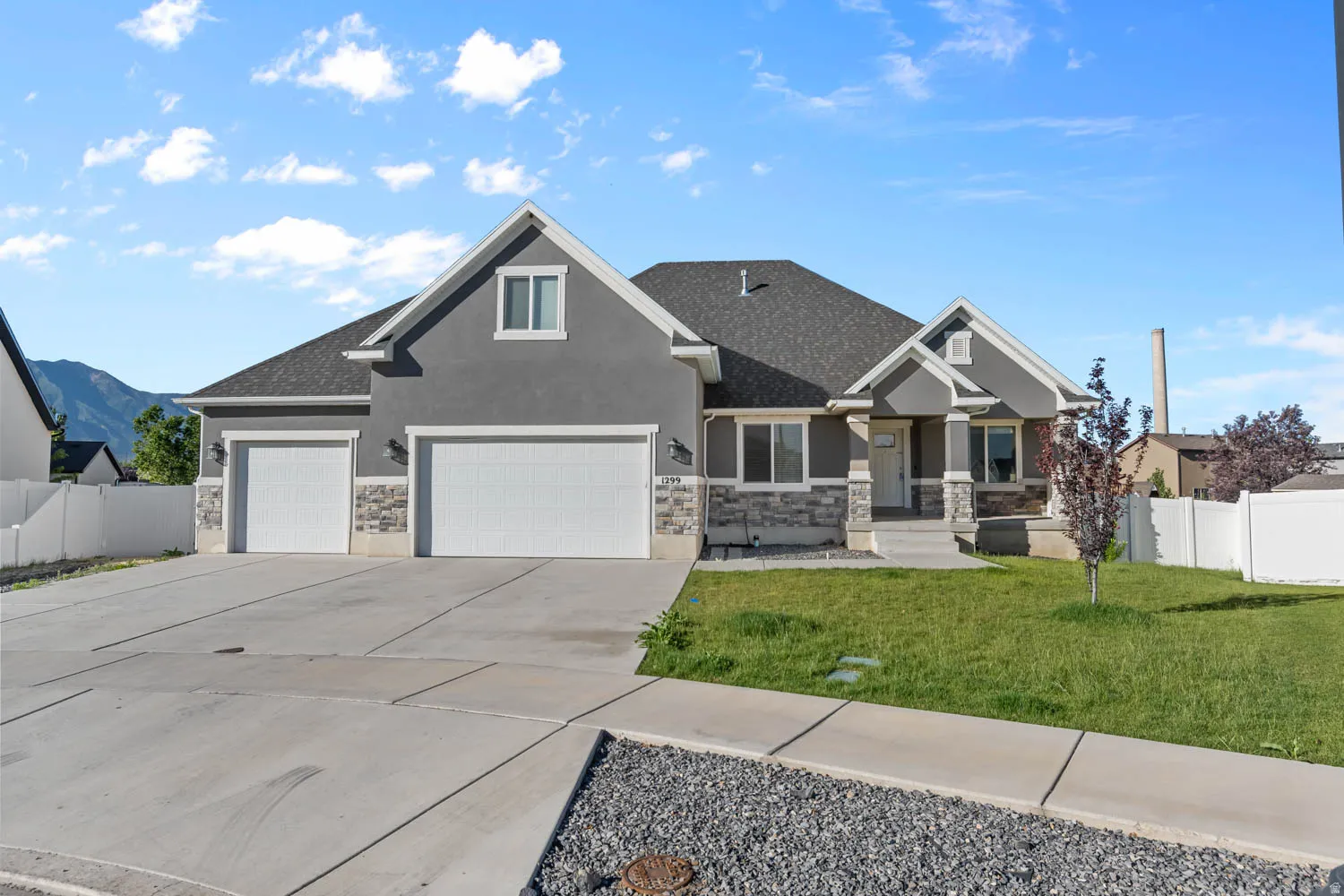 Contemporary exterior with a stone and stucco facade, a two-car garage, a covered front porch, and a concrete driveway