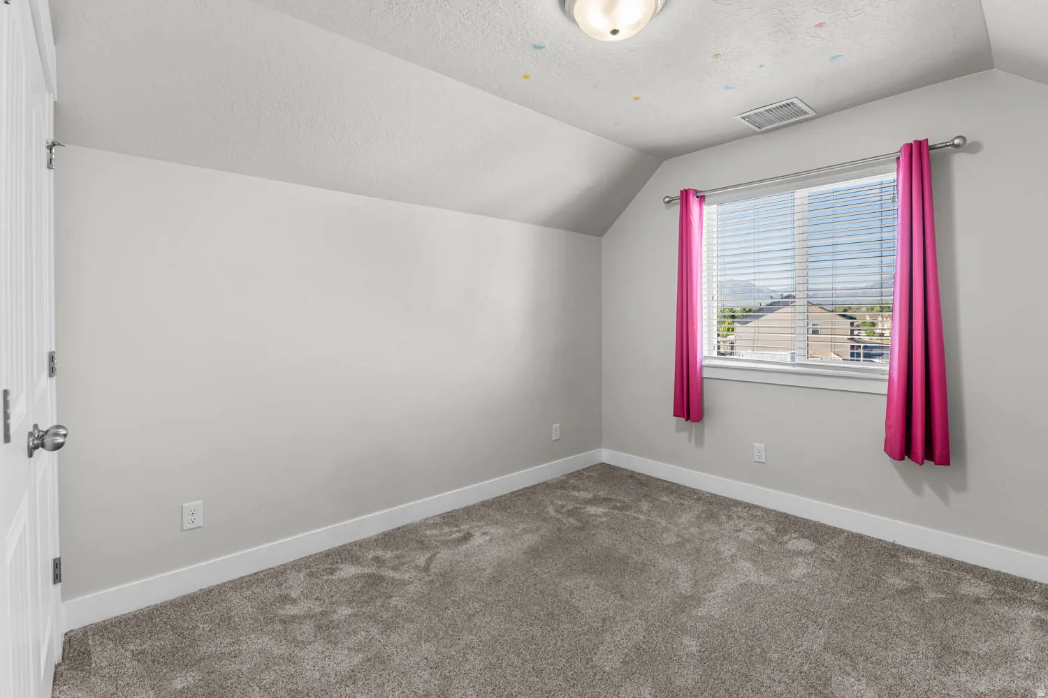 Carpeted room featuring a white window frame, horizontal blinds, and sloped ceiling