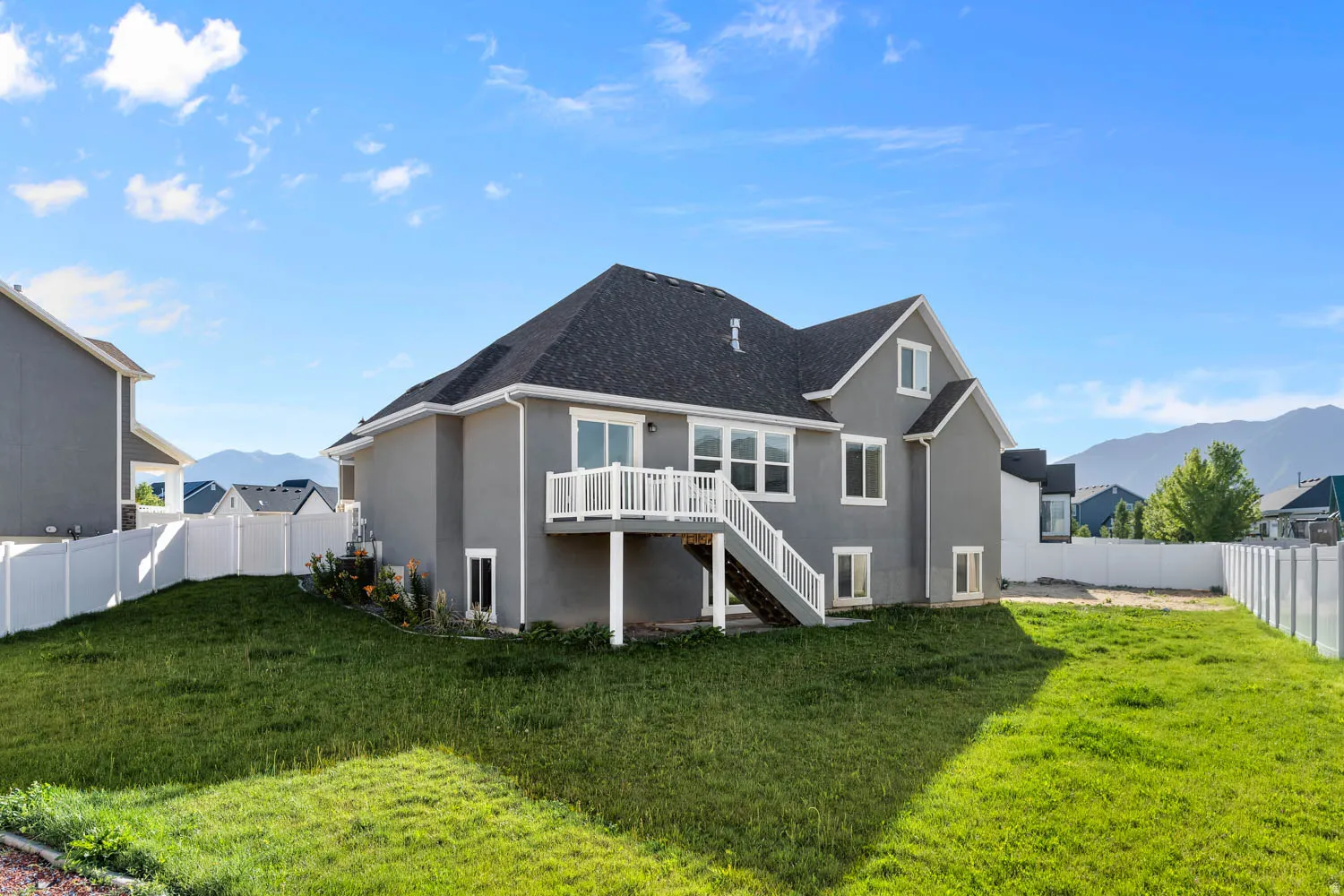 Spacious backyard with a sloped lawn and white vinyl fencing