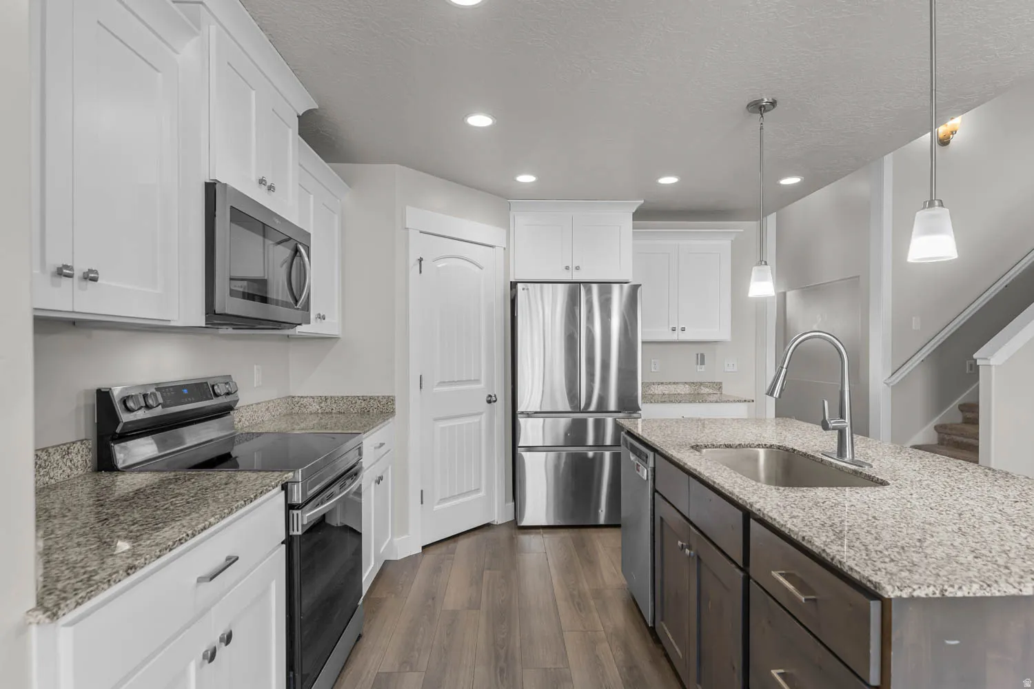 Kitchen featuring white shaker cabinetry, stainless steel appliances, and wood-finish flooring