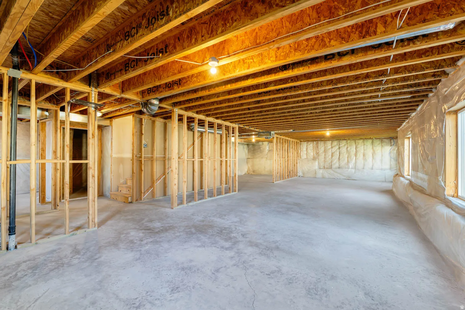 Unfinished basement featuring extensive framing, exposed wood joists, a concrete floor, and multiple windows