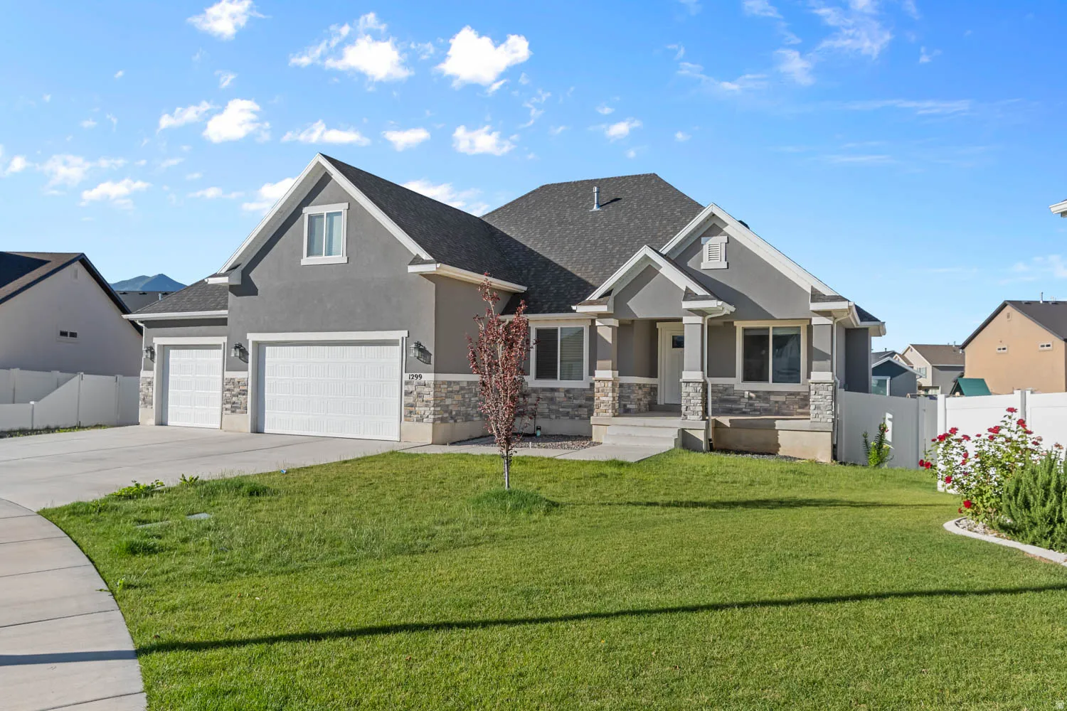 Modern stucco exterior featuring stone accents, a covered entry, and a two-car garage