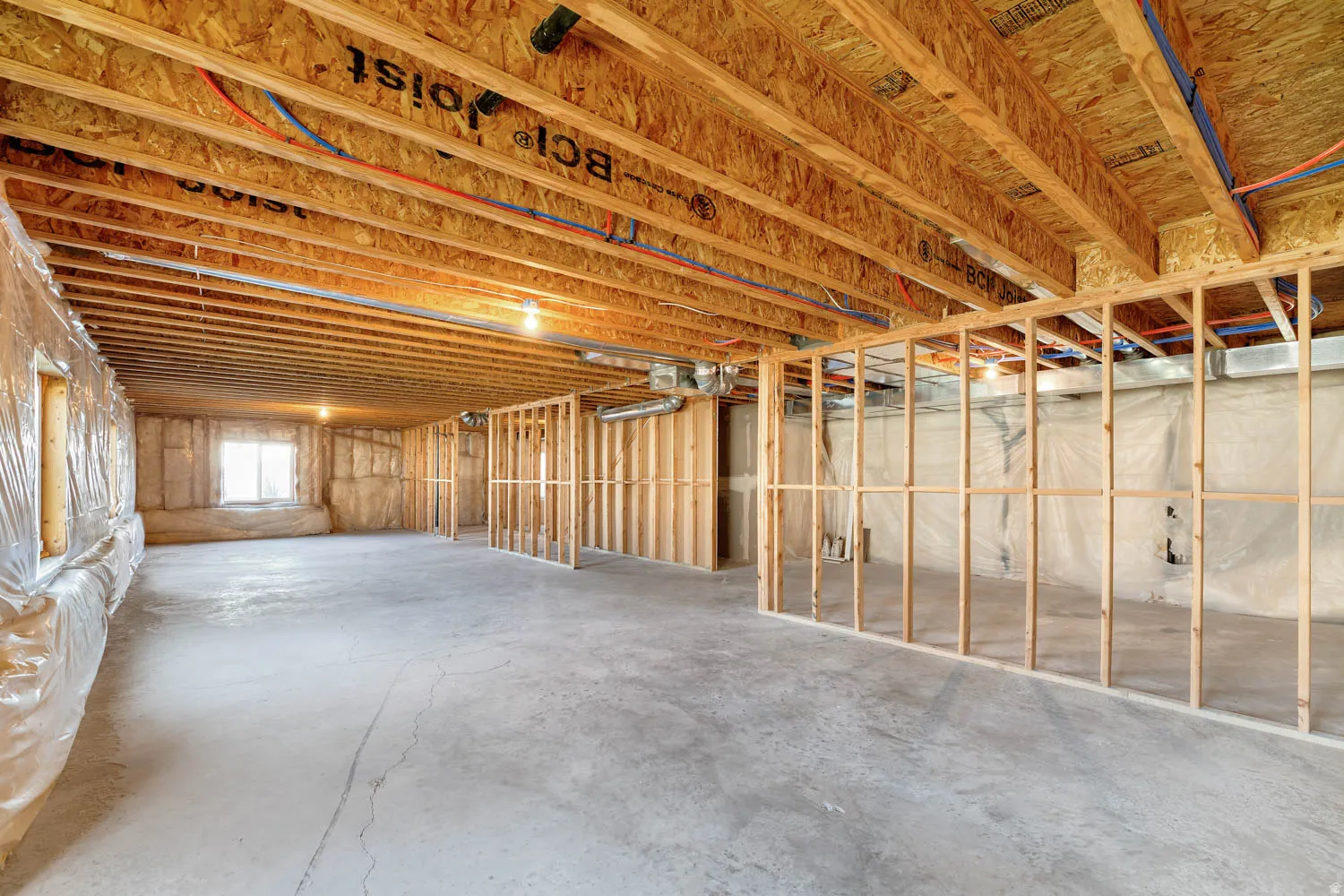 Unfinished basement featuring exposed wood joists, concrete flooring, and framed interior walls