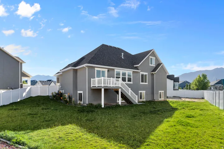 Spacious backyard with a sloped lawn and white vinyl fencing