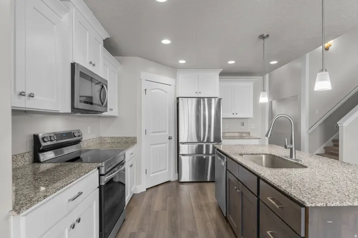 Kitchen featuring white shaker cabinetry, stainless steel appliances, and wood-finish flooring