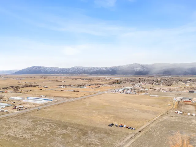 Expansive rural landscape featuring a mountainous backdrop, open fields, and distant structures under a broad sky