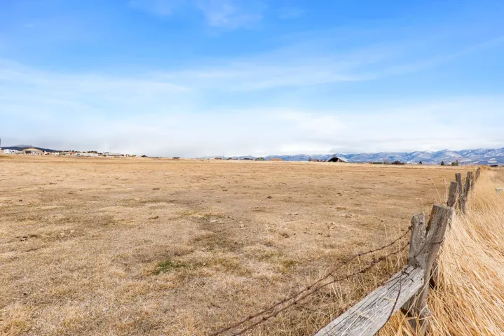 Expansive open land with a rustic barbed wire fence and dry grasses