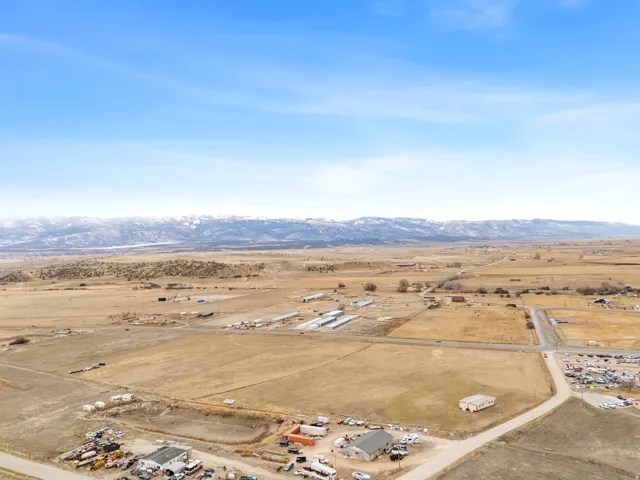 Expansive land parcel featuring open fields, a natural pond, and mountain range backdrop