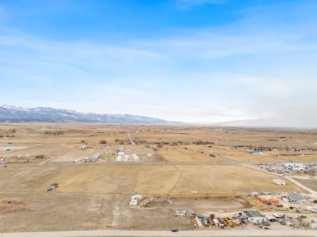 Expansive land parcel featuring a paved road frontage and distant mountain ranges