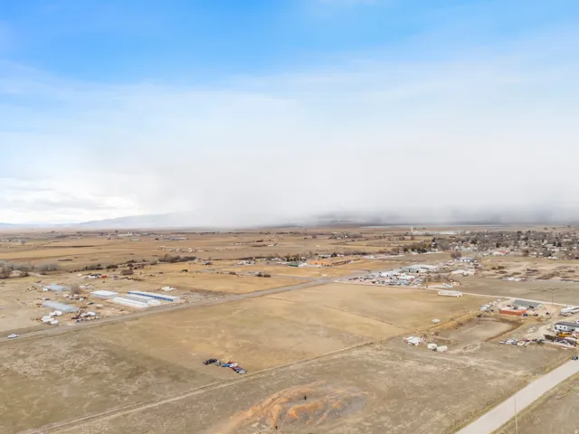 Expansive agricultural land featuring a mix of open fields, scattered buildings, and distant mountain ranges