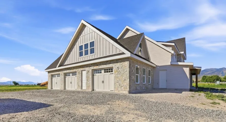 Stone and siding exterior featuring a three-car garage with carriage-style doors and upper window panels