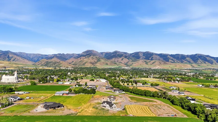 Expansive aerial landscape featuring a large community with developing residential areas, surrounded by green agricultural fields