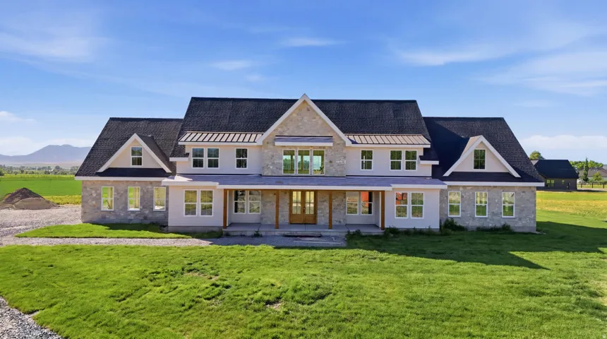 Modern farm-style residence featuring a prominent stone facade, dark shingle roof, and multiple gabled dormers