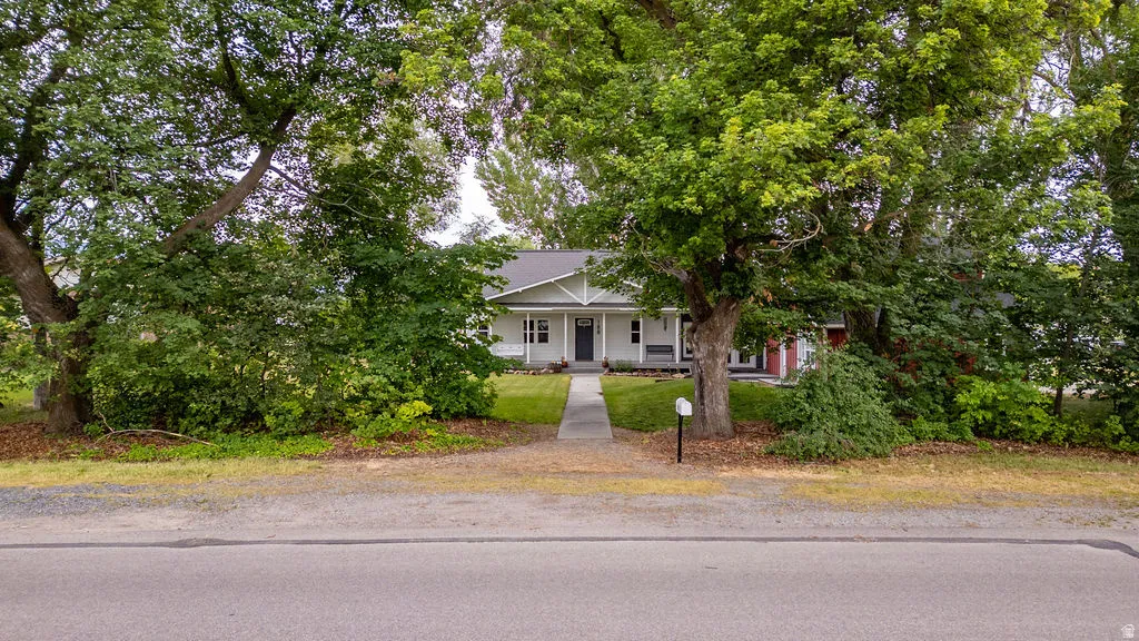 White exterior residence with a dark front door, a covered front porch, and a dormer window