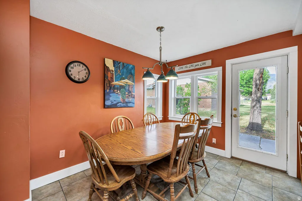 Dining area featuring tiled flooring, a multi-light pendant fixture, white trim, and a glass-paneled exterior door