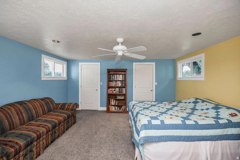 Carpeted room featuring dual windows with white trim, a ceiling fan with integrated lighting, recessed lighting, and two panel doors