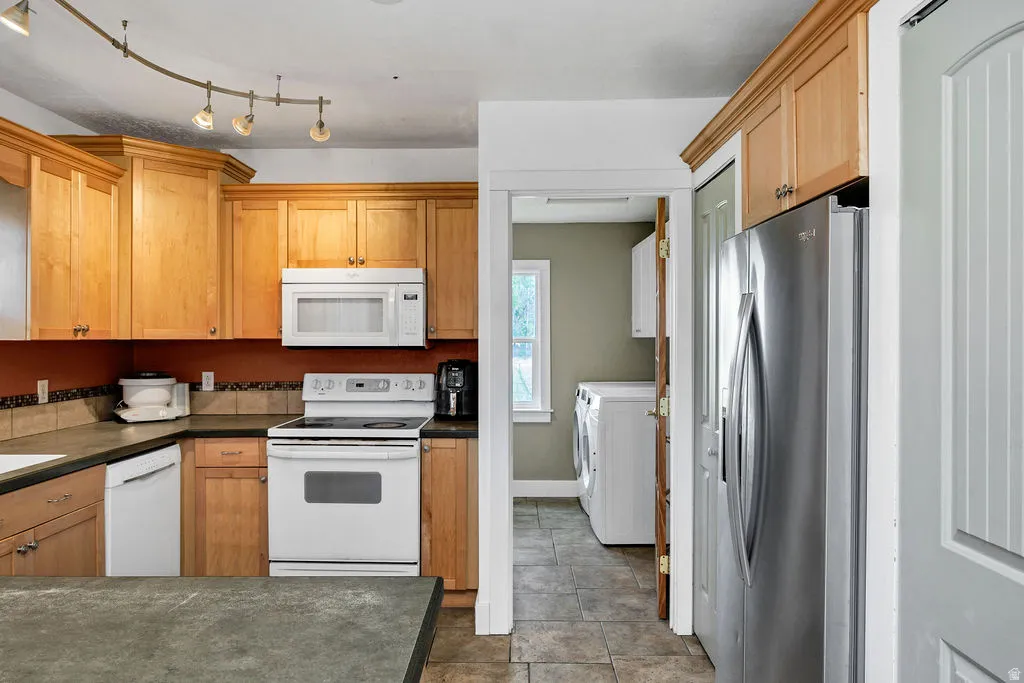 Kitchen featuring wood cabinetry, track lighting, stainless steel refrigerator, and built-in microwave