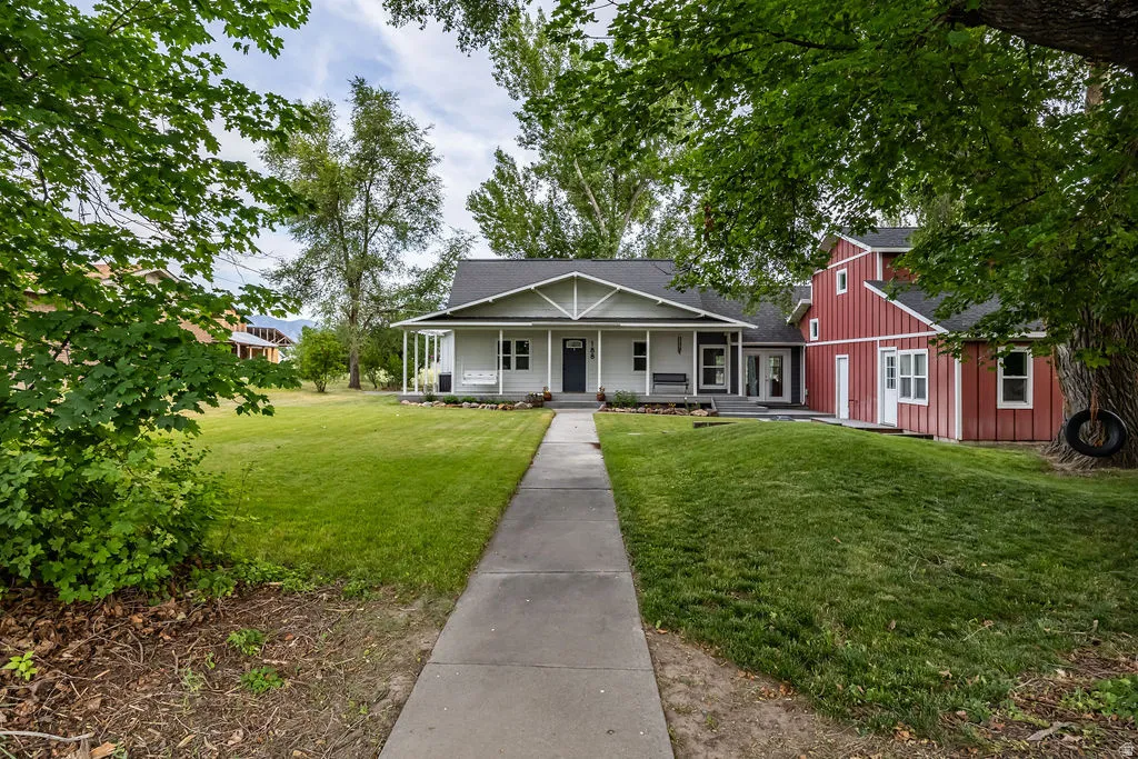Cottage-style residence featuring a covered front porch and a distinctive red board and batten addition