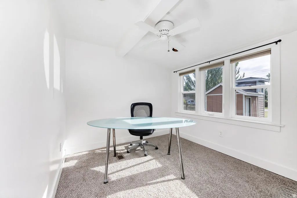 Bright room featuring three sash windows, a ceiling fan, white trim, and light-toned carpeting
