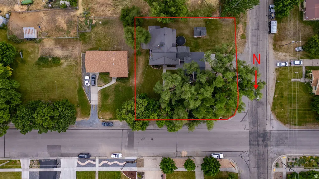 Aerial view showcasing a corner lot property with mature tree coverage