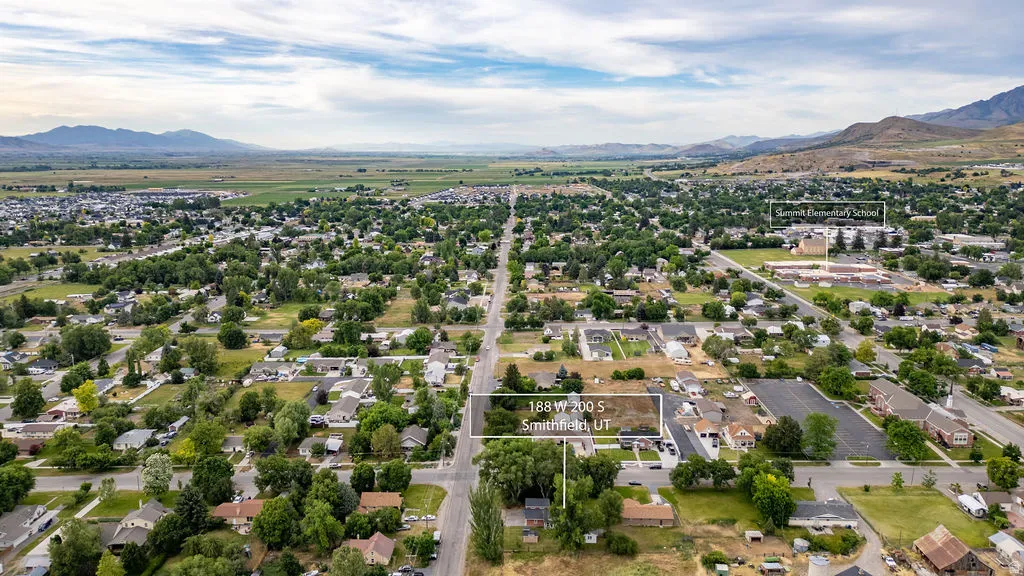 Expansive aerial perspective showcasing a residential community with abundant mature trees and mountainous backdrops