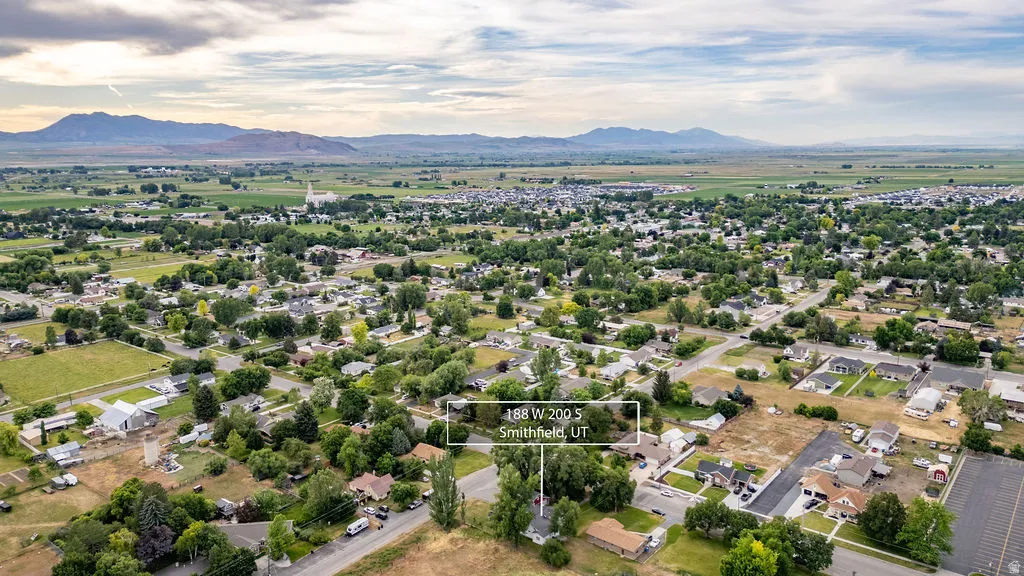 Residential area featuring established trees, paved roads, and distant mountains