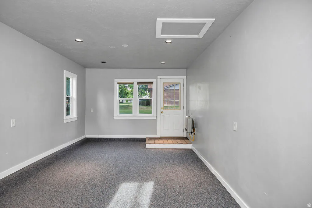 Versatile room on south side of garage featuring light grey walls, recessed ceiling lighting, and durable speckled flooring