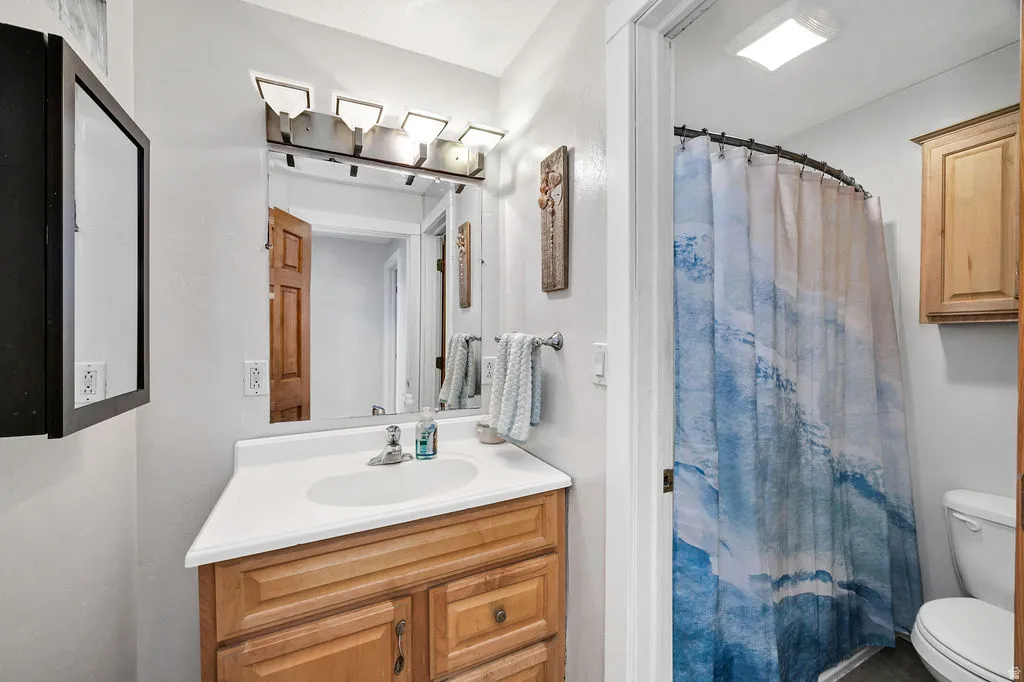 Hall bathroom featuring a vanity with wood-finish cabinetry, a white countertop, and an integrated sink