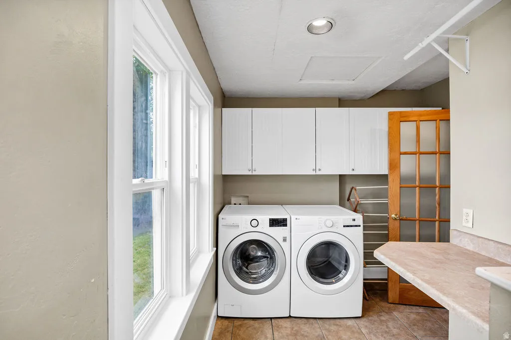 Dedicated laundry area featuring white upper cabinetry, a light-toned countertop, and tiled flooring