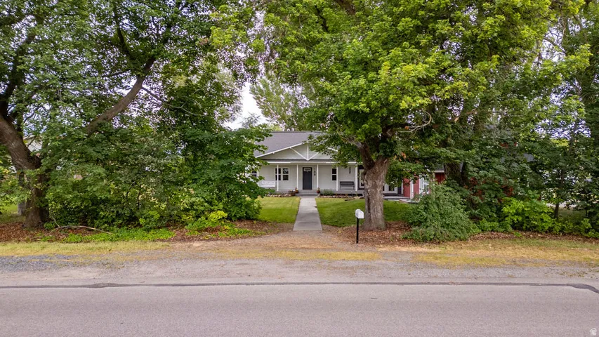 White exterior residence with a dark front door, a covered front porch, and a dormer window
