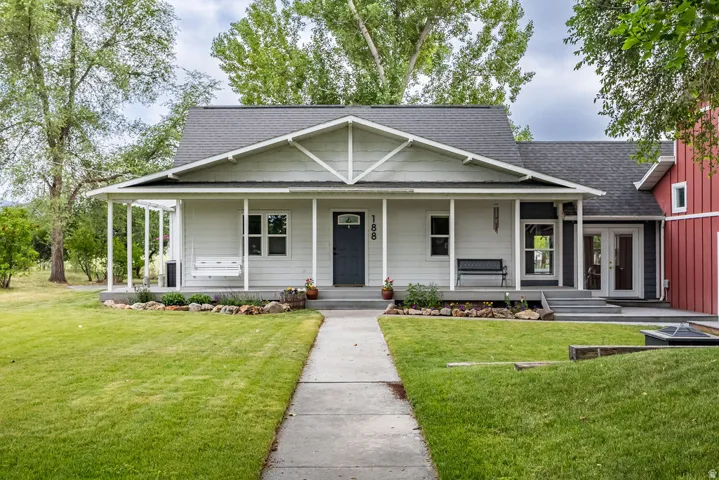 Siding exterior with a covered front porch featuring a porch swing, dark gray entry door, and stone-accented landscaping