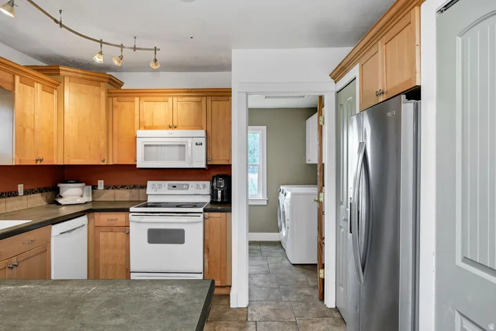 Kitchen featuring wood cabinetry, track lighting, stainless steel refrigerator, and built-in microwave