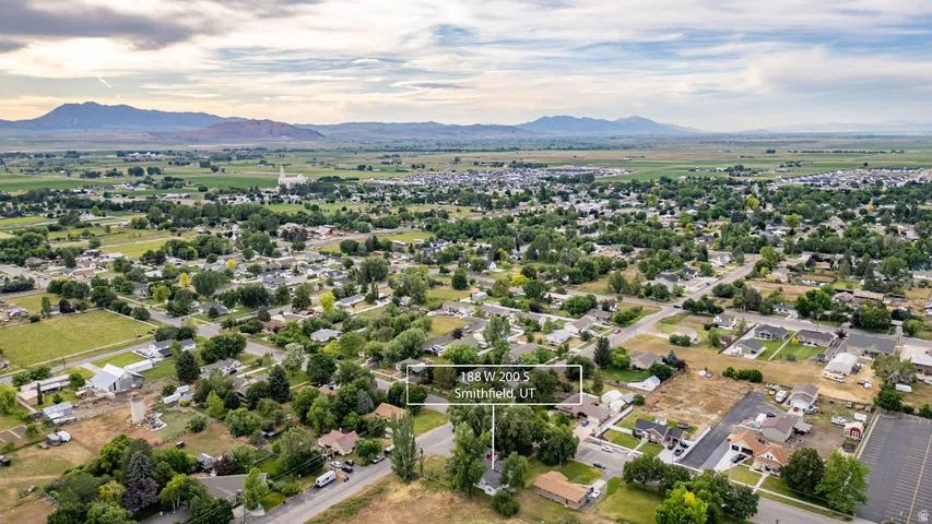 Residential area featuring established trees, paved roads, and distant mountains