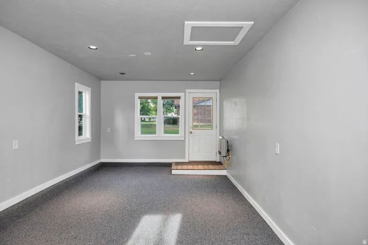 Versatile room on south side of garage featuring light grey walls, recessed ceiling lighting, and durable speckled flooring