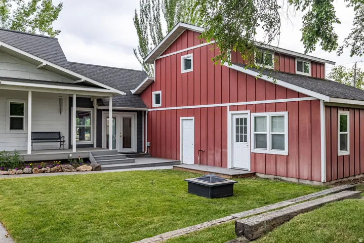 Exterior featuring a red board-and-batten section with white trim, a light-colored horizontal siding section, and dark gray roofing