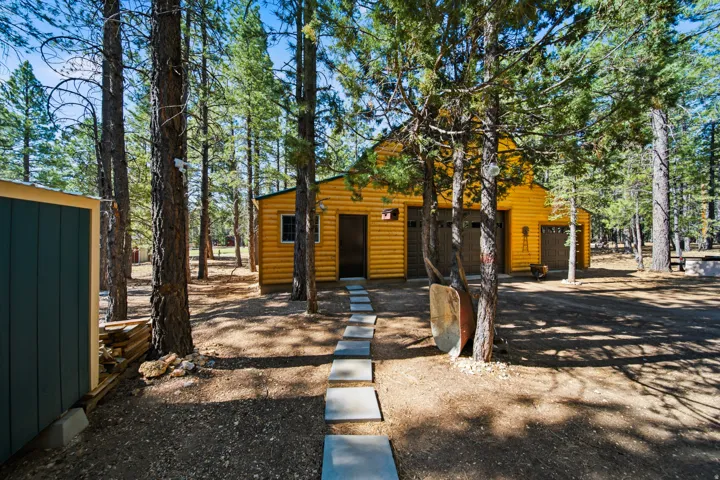 Wood-sided structure featuring multiple garage bays, a pedestrian door, and a paver pathway
