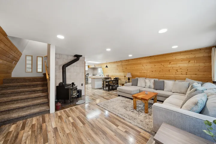 Open-concept living space featuring wood-finish flooring, recessed lighting, and a wood-paneled accent wall