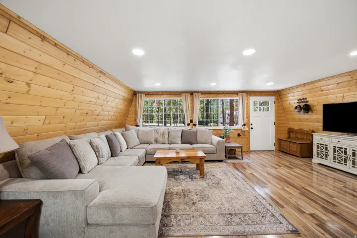 Living area featuring wood-finish flooring, recessed ceiling lighting, and natural wood paneling