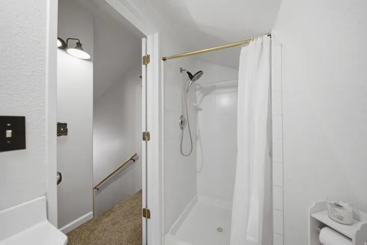 Walk-in shower with white subway tile surround and a gold-finish shower rod