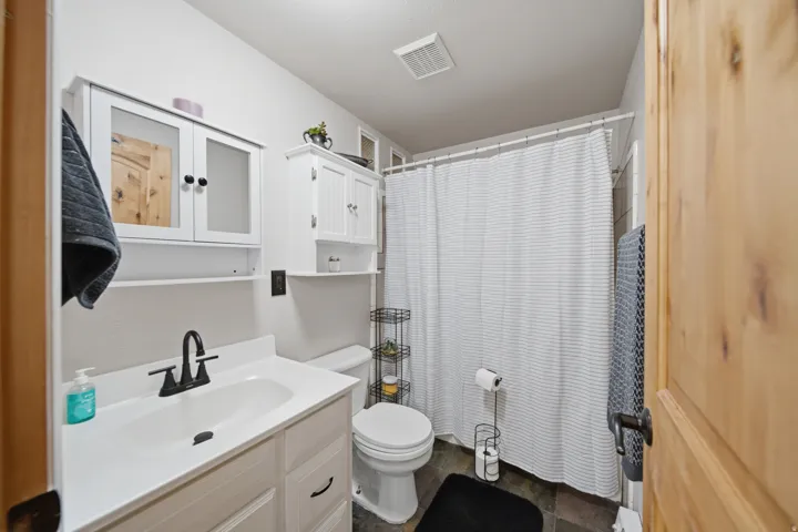 Bathroom featuring a white vanity with integrated sink, black matte faucet, and ample storage from wall-mounted cabinetry