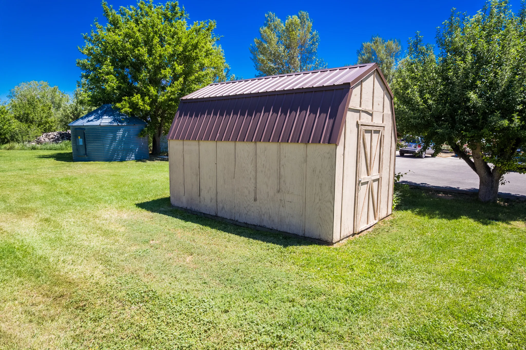 Light-colored storage shed featuring a barn-style roof with brown metal roofing