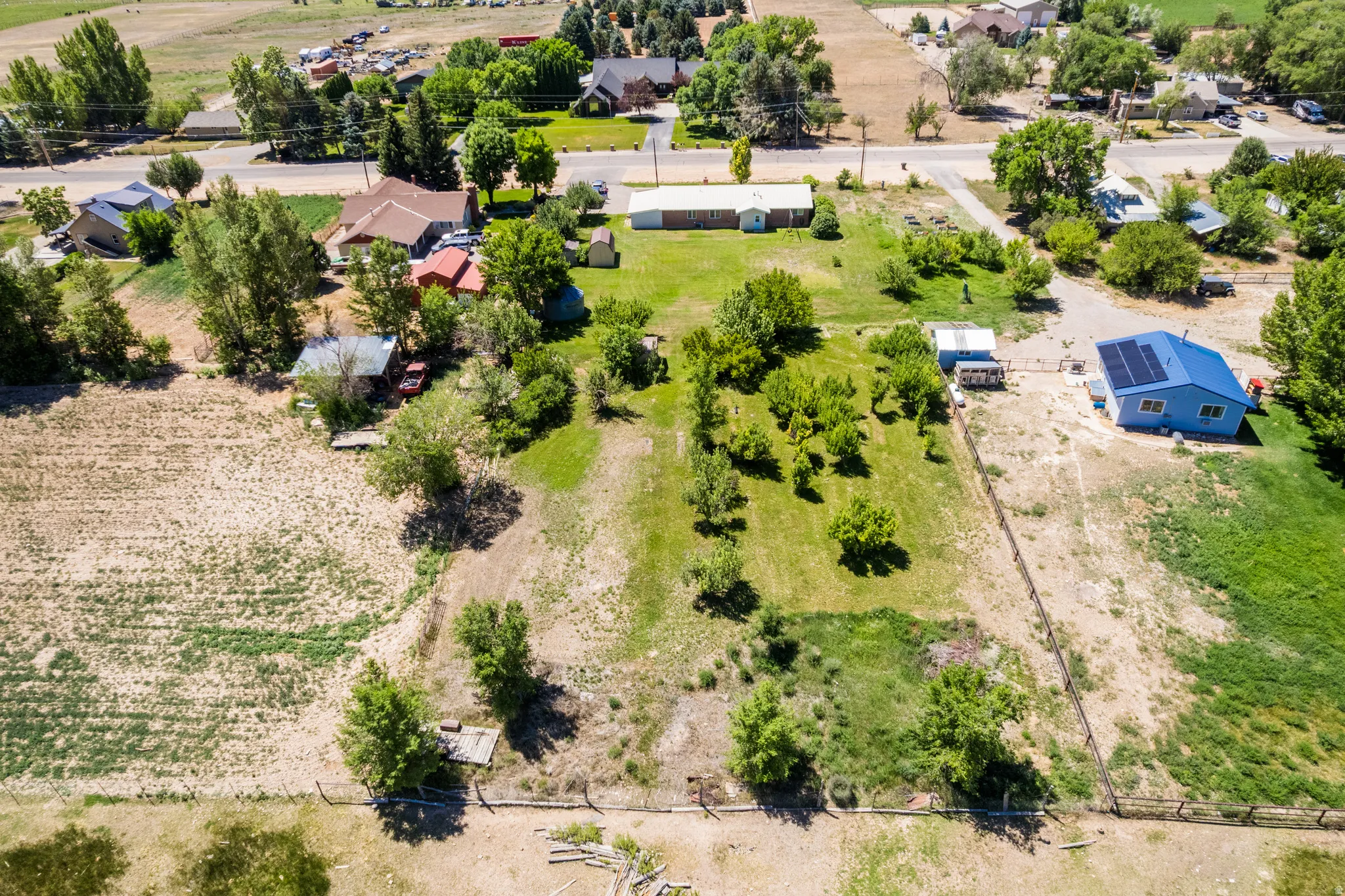 Expansive property featuring a mix of cultivated and natural terrain, bordered by fencing