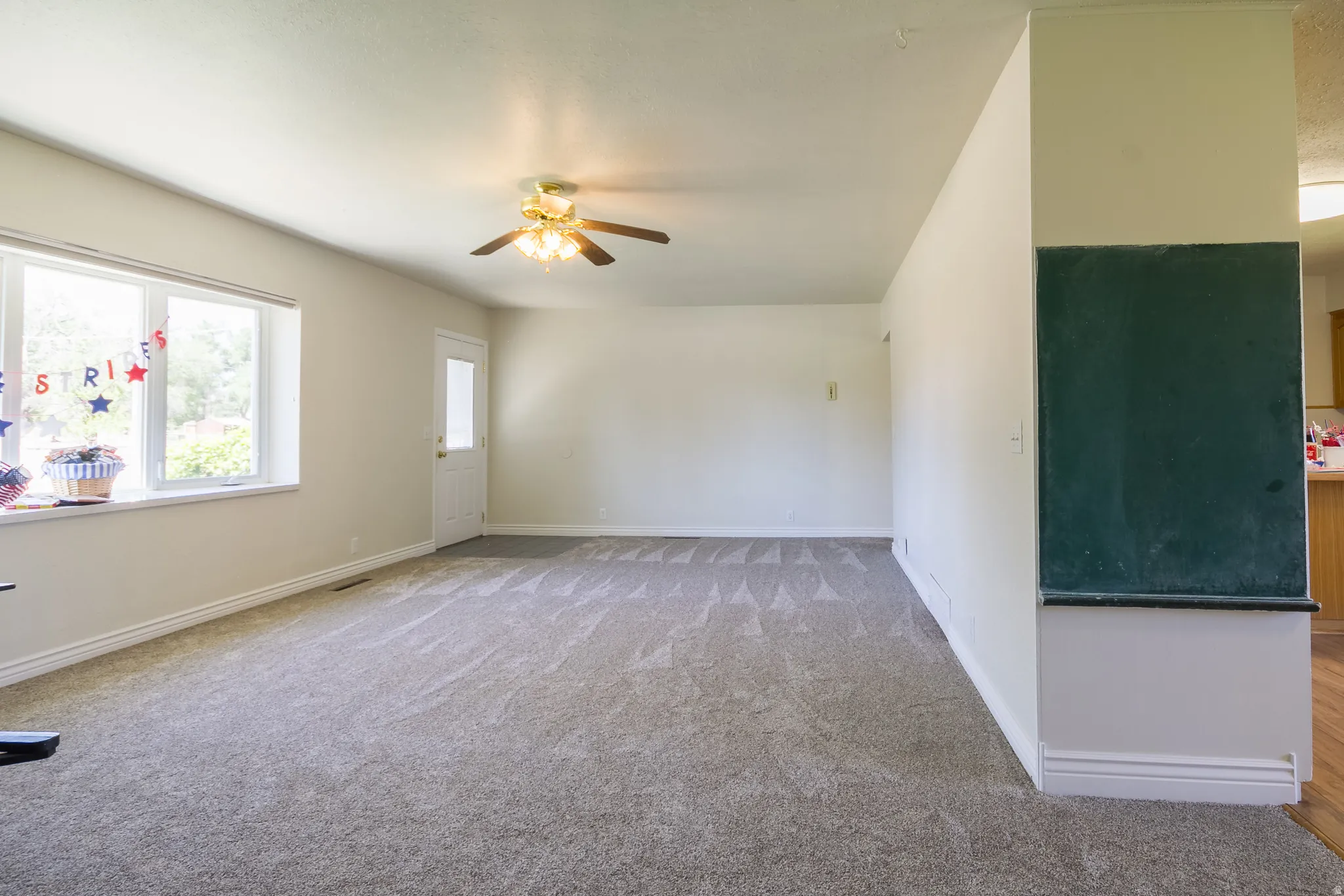 Spacious living area featuring neutral carpeting and abundant natural light from a large picture window