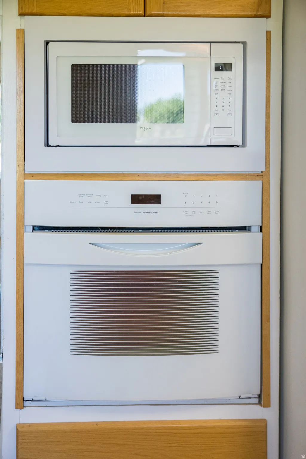 Built-in microwave and wall oven combination unit, integrated into cabinetry with wood-finish framing