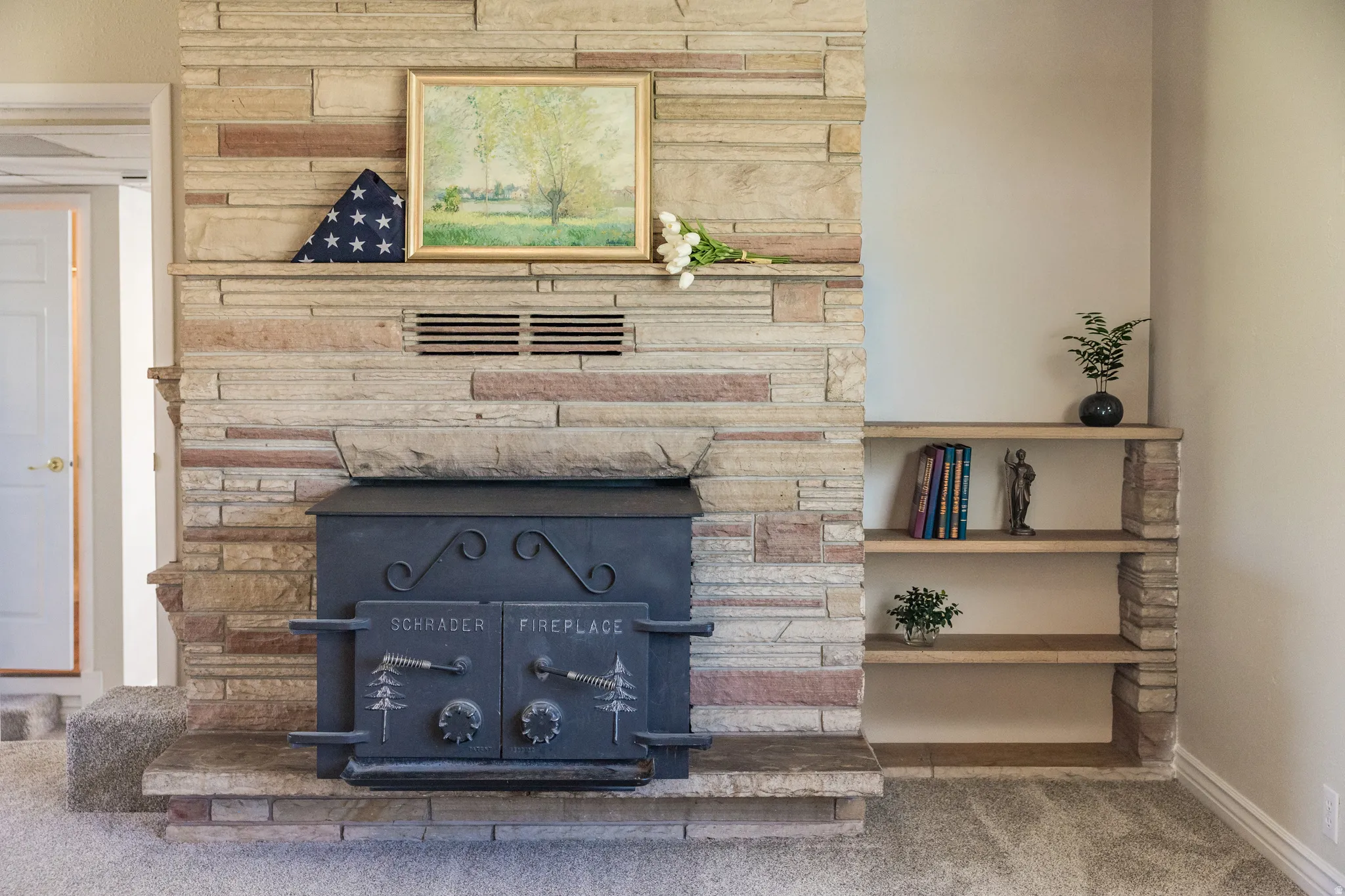 Stone-clad fireplace featuring a cast iron wood-burning insert