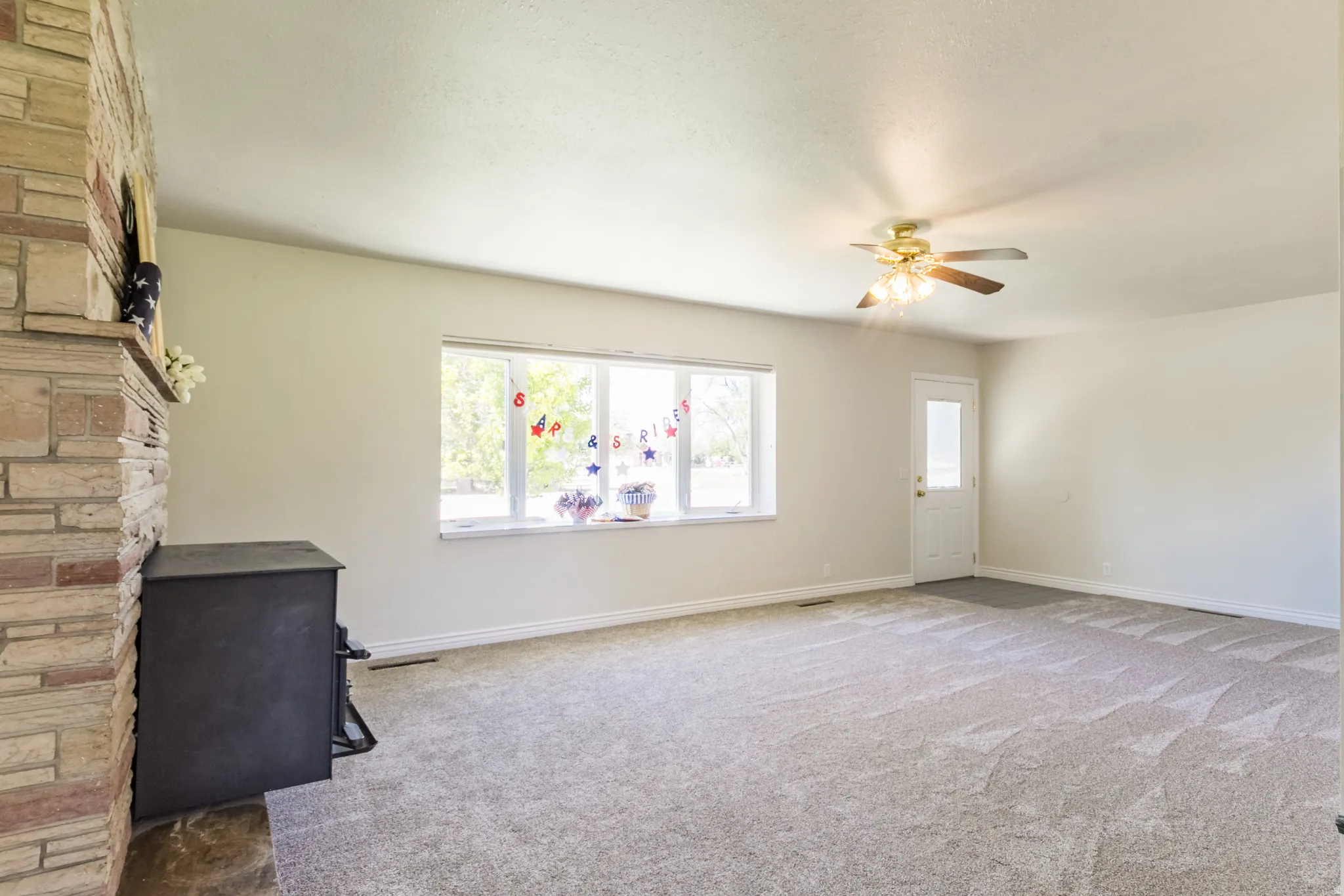 Spacious living area featuring light neutral walls and gray patterned carpet