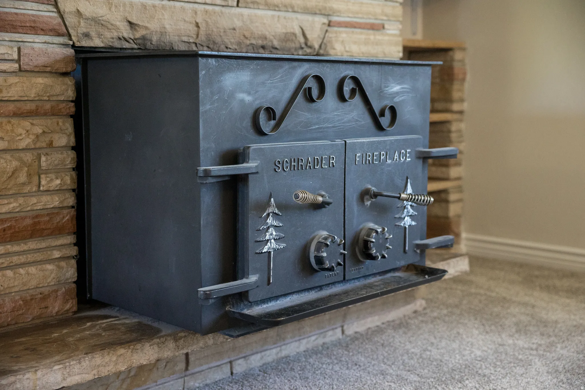 Built-in Schrader fireplace with stone surround, a stone hearth, and decorative metalwork