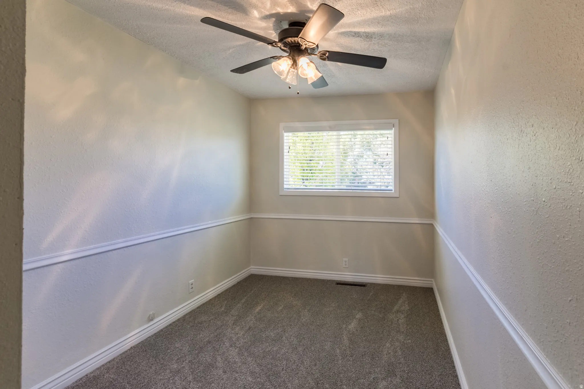 Room featuring a ceiling fan with integrated lighting, a window with horizontal blinds, carpet flooring, baseboard trim, and chair rail molding