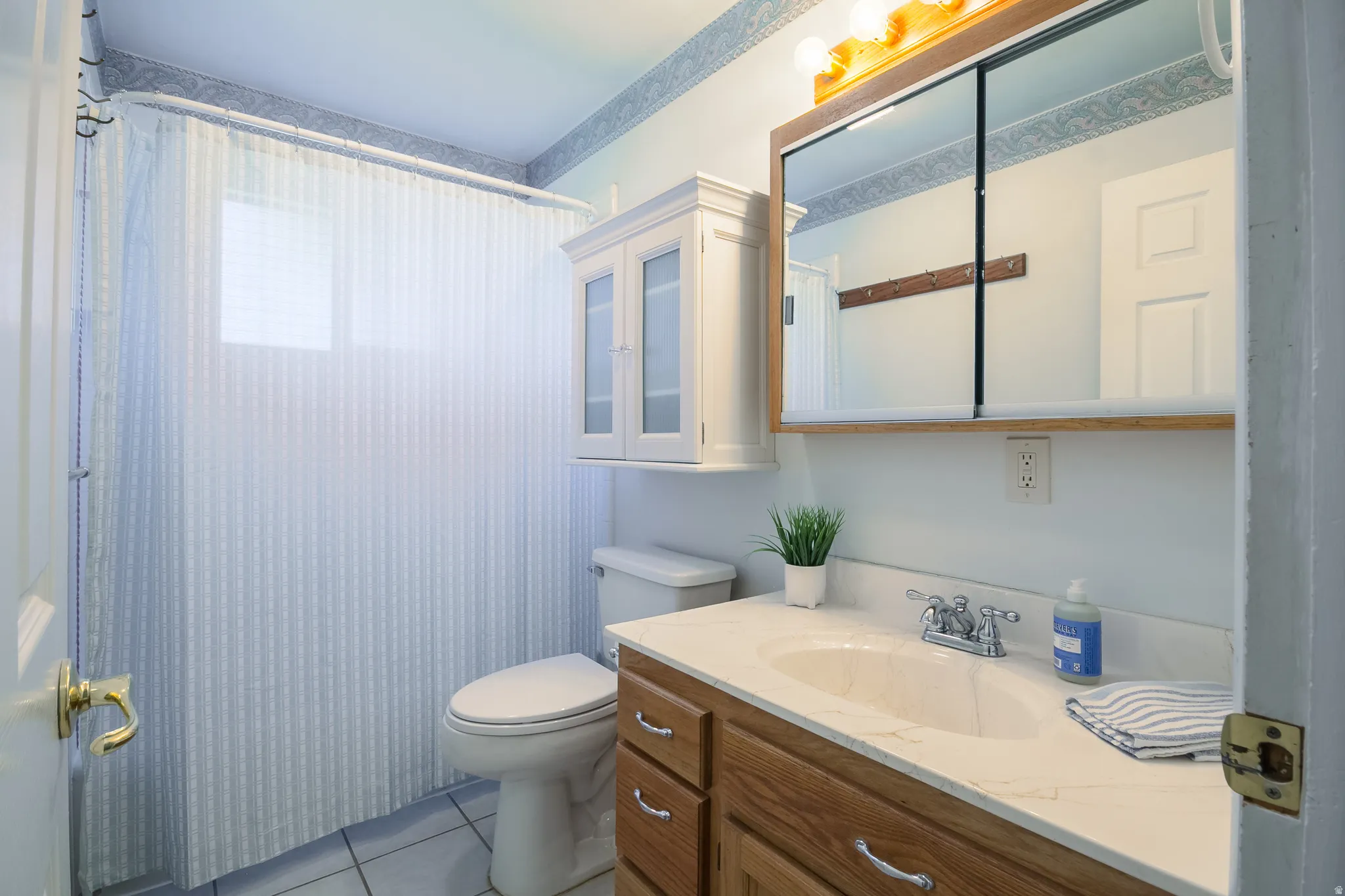 Bathroom featuring a wood-finish vanity with a built-in sink, a wall-mounted medicine cabinet with a wood-finish frame, and overhead vanity lighting