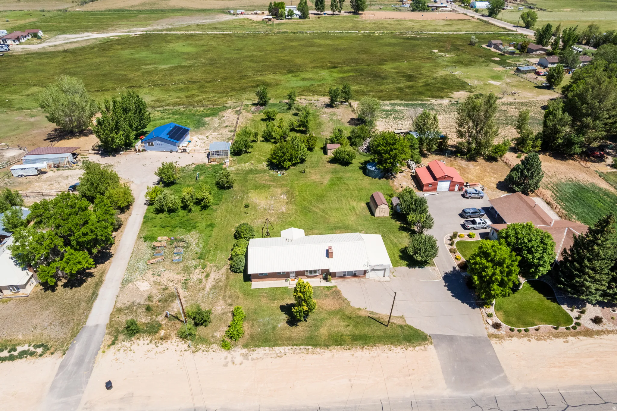 Expansive property featuring a main residence with an attached garage, a separate red barn structure, and a secondary building with solar panels
